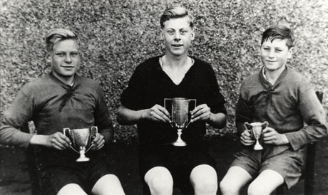 Photograph showing three boys, aged approximately fourteen years, sitting in front of a wall, each holding a trophy cup; the photograph has been identified as Sports Champion, Wheatley Hill