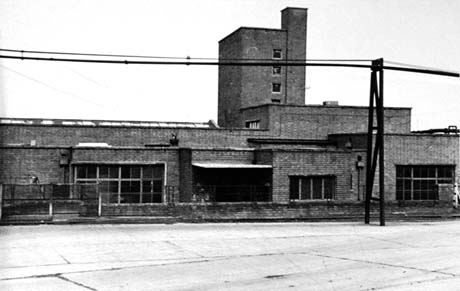 Photograph of the exterior of a flat-roofed, brick building with three large windows and a tower with small windows in it; the building has been identified as the pithead baths at Wheatley Hill