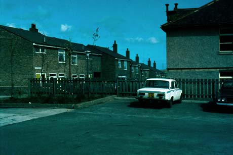 Photograph showing, in the foreground, two cars parked on a parking place; one car has the registration number PTF 47M; on the left of the picture is a row of terraced houses running away from the camera; the houses appear to have been built in the 1970s; the photograph has been identified as Patton Street, Wheatley Hill