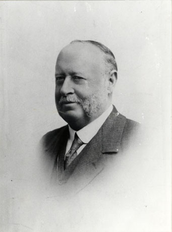 Photograph of the head and shoulders of a middle-aged man; his hair is receding and he has a moustache and whiskers on the side of his face but his chin is clean-shaven; he is wearing a stiff collar and tie and a jacket and waistcoat; he has been identified as Mr. Armstrong, Junior, of Wingate