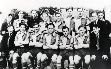 Photograph of eleven men wearing football strip posed with five other men wearing suits and ties; they have been identified as members of Wingate Amateur Football Club