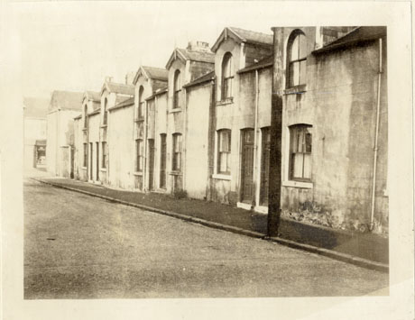 Photograph of the facade of six terraced houses with a doorway, one window on the ground floor and a dormer window; they have been identified as Chapel Square, Wingate