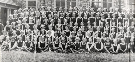 Photograph showing one hundred and five girls and school mistresses, posed outside buildings identified as the A. J. Dawson Grammar School; it is likely that the photograph adjoins wing0137 on the right